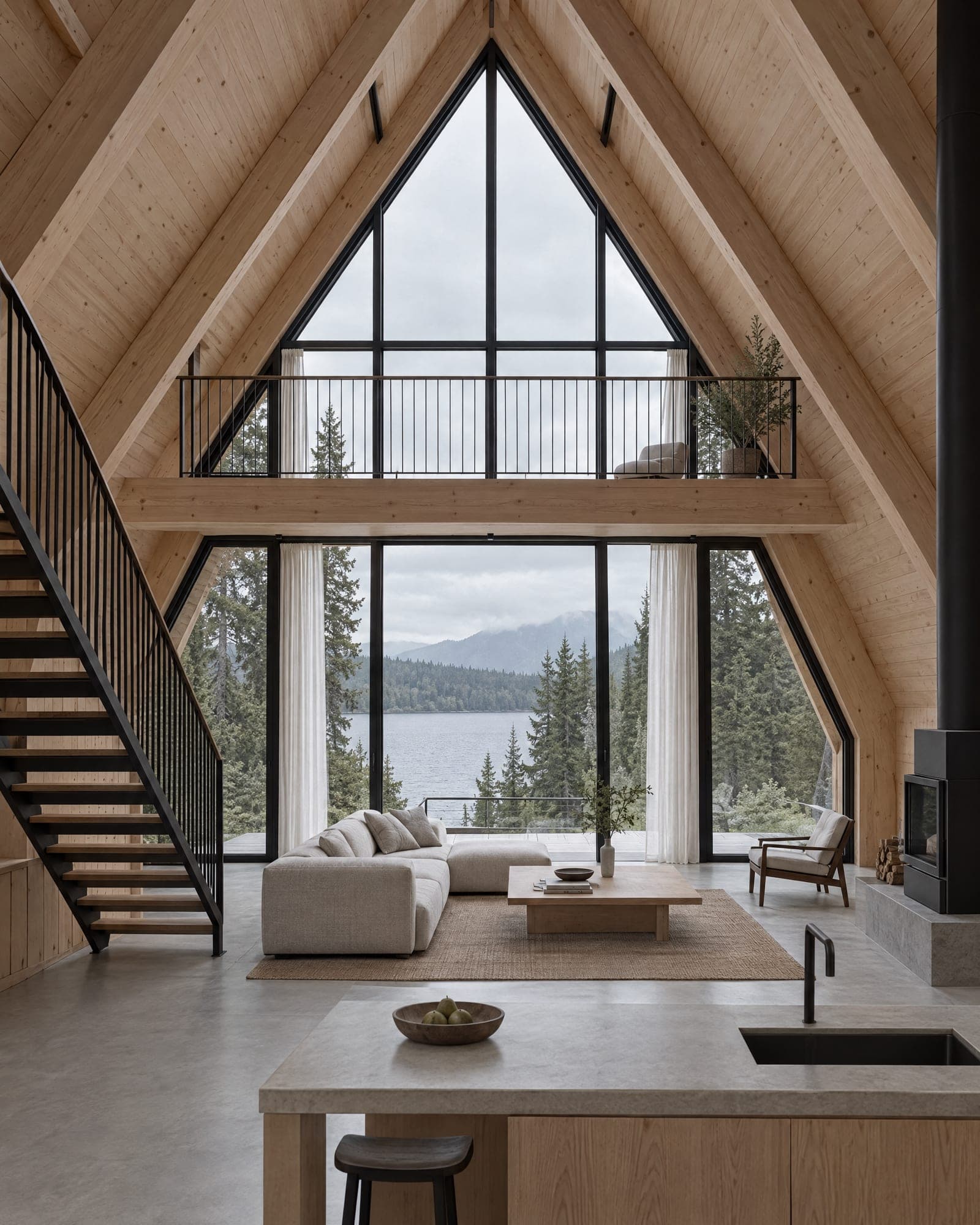 Double-height living room of The Two with a balcony crossing the glazed gable and a view to a grey lake
